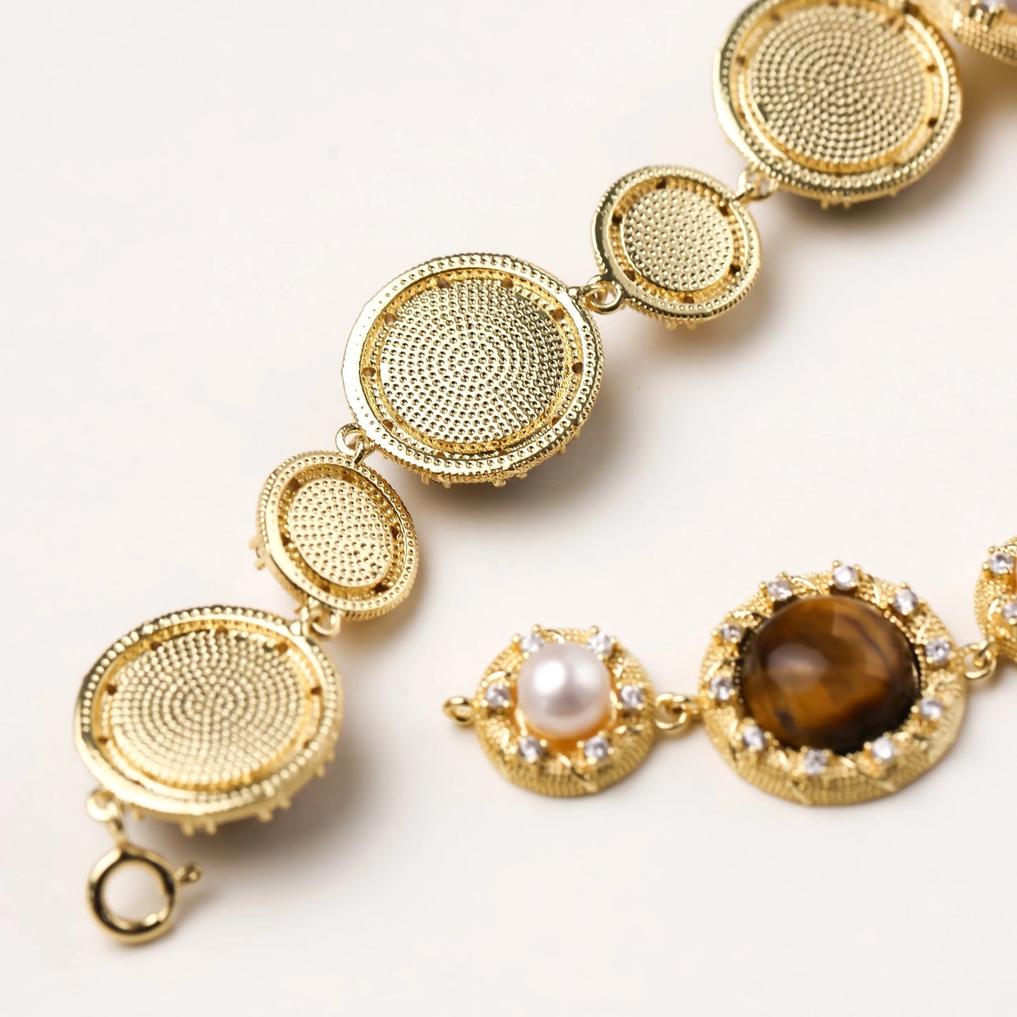 Ornate gold-plated bracelet with alternating brown tiger's eye stones and white freshwater pearls in crystal-accented settings