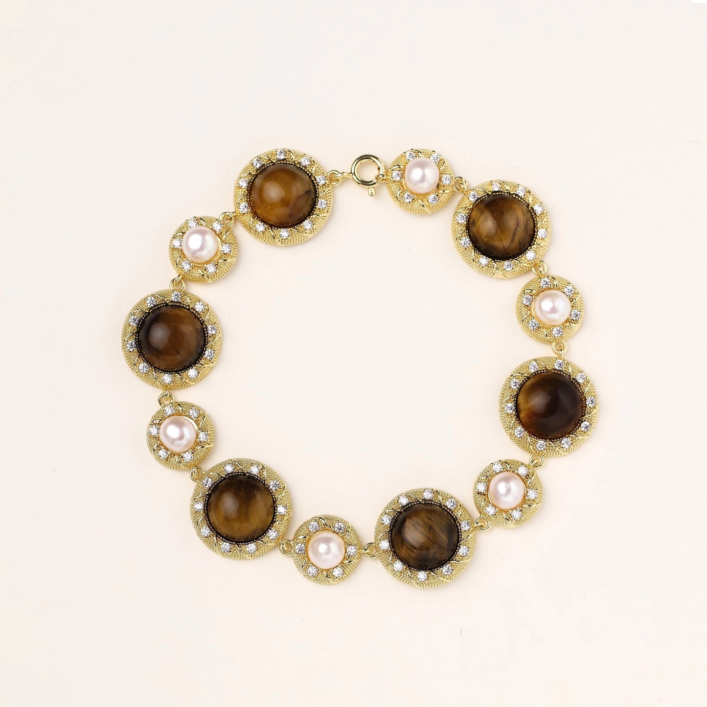 Ornate gold-plated bracelet with alternating brown tiger's eye stones and white freshwater pearls in crystal-accented settings