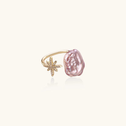 Adjustable ring with lavender baroque pearl and crystal star charm on gold-plated band against cream background.