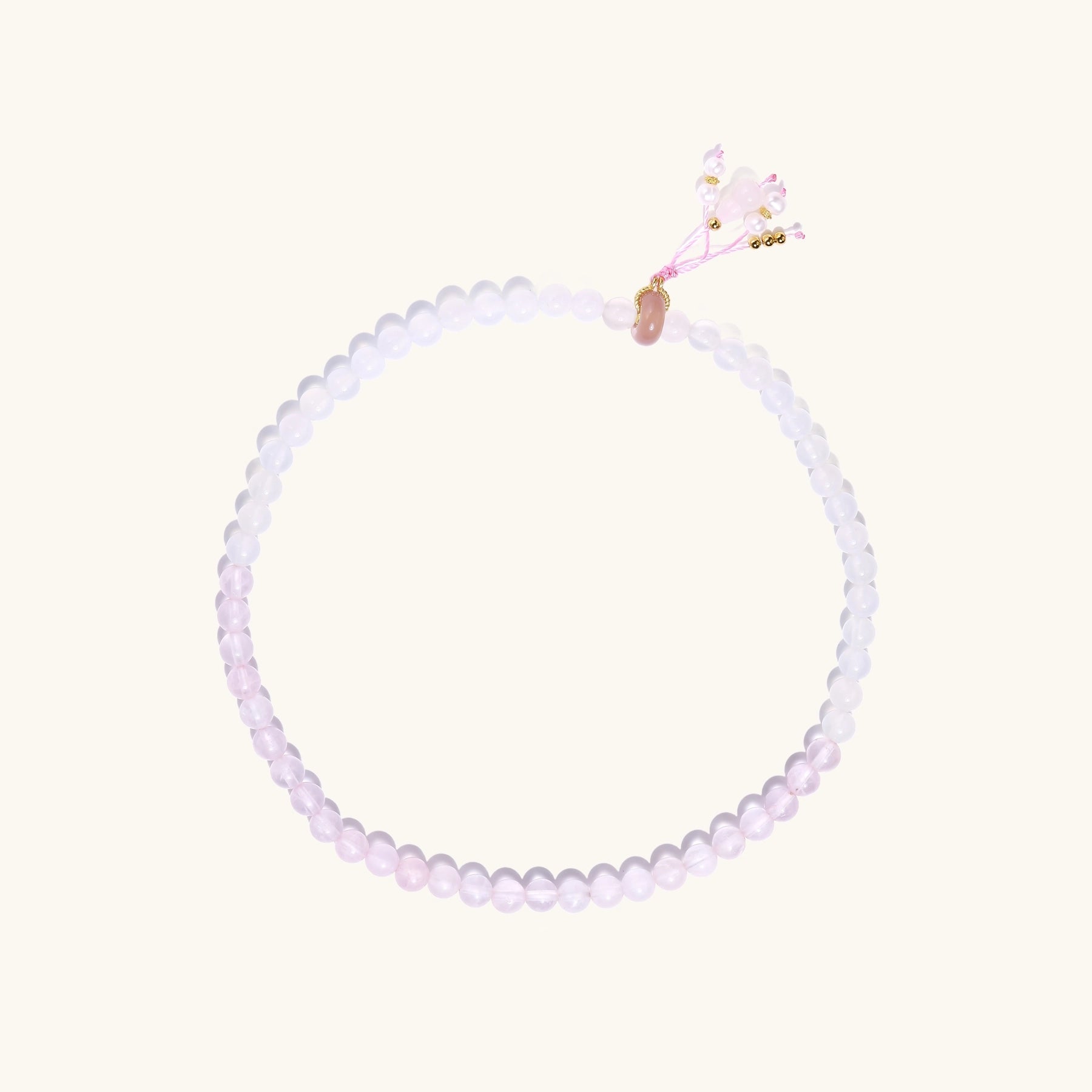 Stretchable bracelet with pink rose quartz and white agate beads, featuring a decorative tassel pendant on white background.