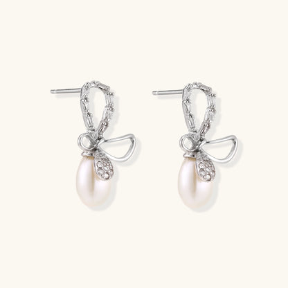 Sterling silver stud earrings with baguette crystal bow design and freshwater pearl drops on white background