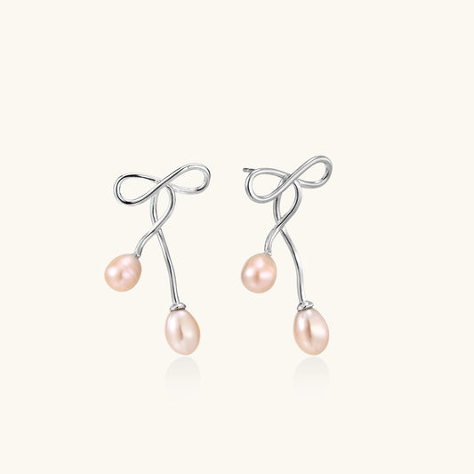 Delicate sterling silver wire earrings with organic bow shapes and two pink freshwater pearls on white background