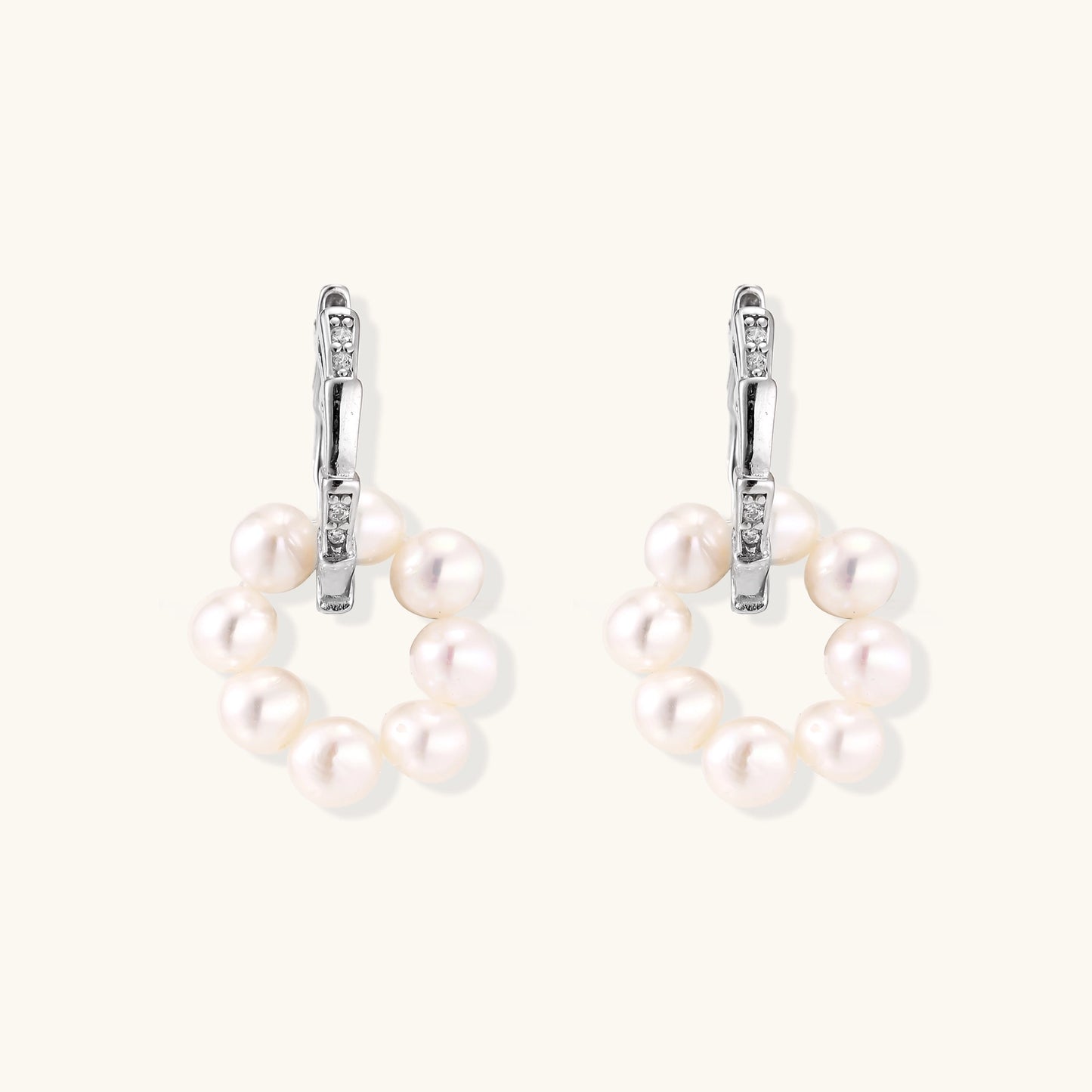 Sterling silver huggie hoop earrings with clustered white freshwater pearls and crystal accents on white background.