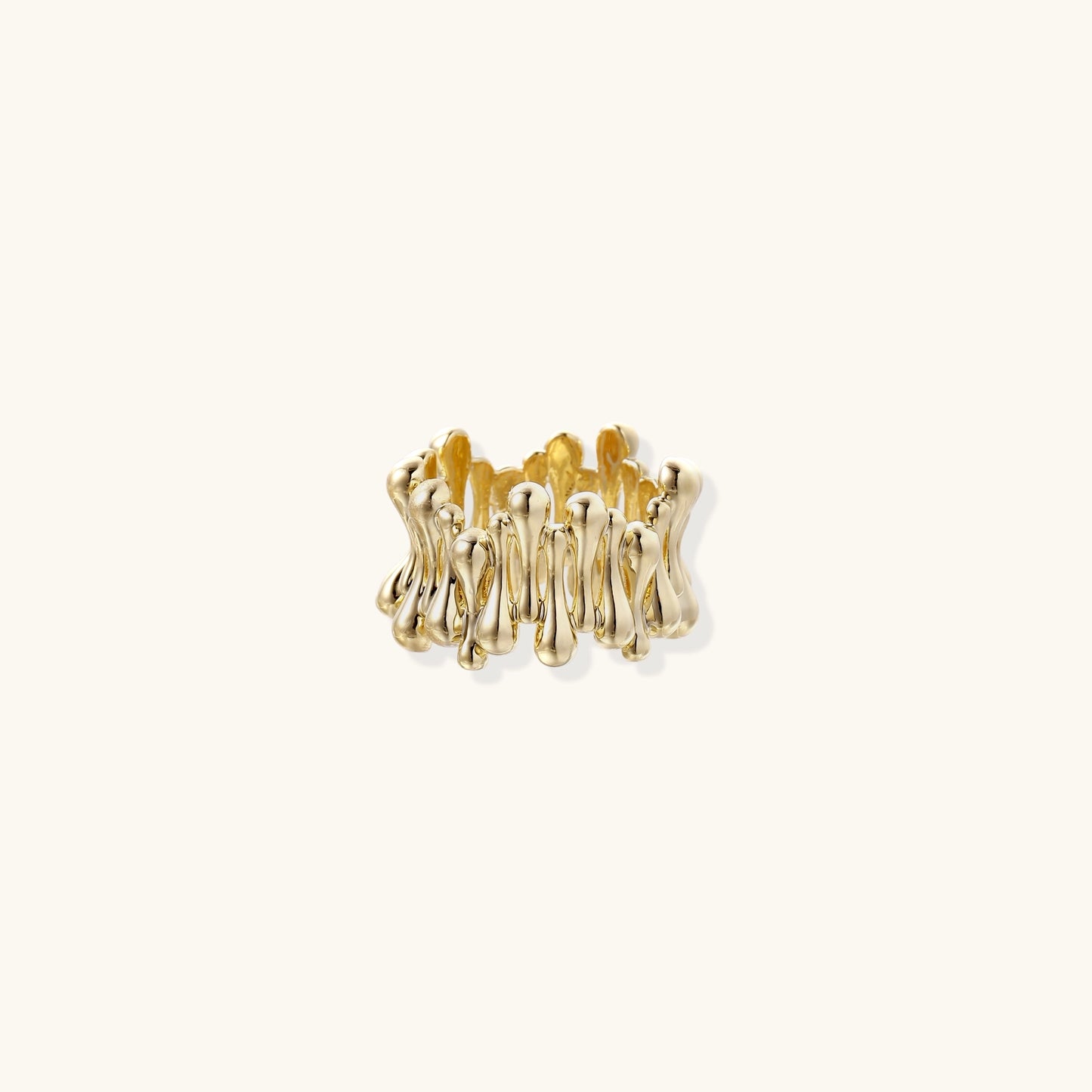 Close-up of chunky 18K gold-plated brass ring with flowing wave-like sculptural design on neutral background.