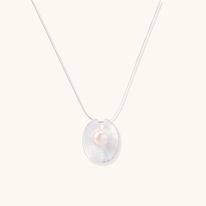Delicate sterling silver necklace with oval iridescent pendant and central freshwater pearl on white background