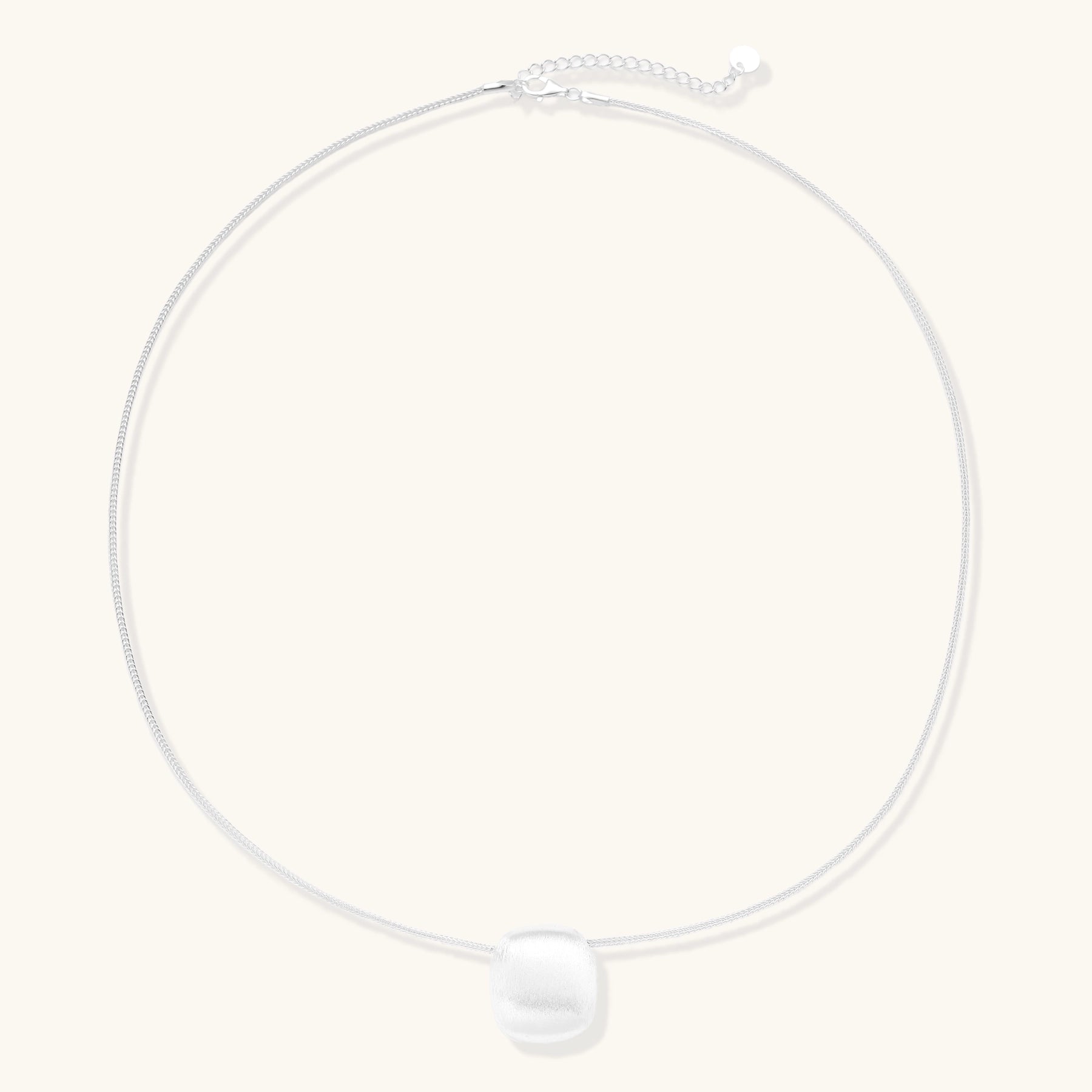 Minimalist sterling silver necklace with brushed square pendant on adjustable chain against white background.