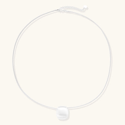 Minimalist sterling silver necklace with brushed square pendant on adjustable chain against white background.