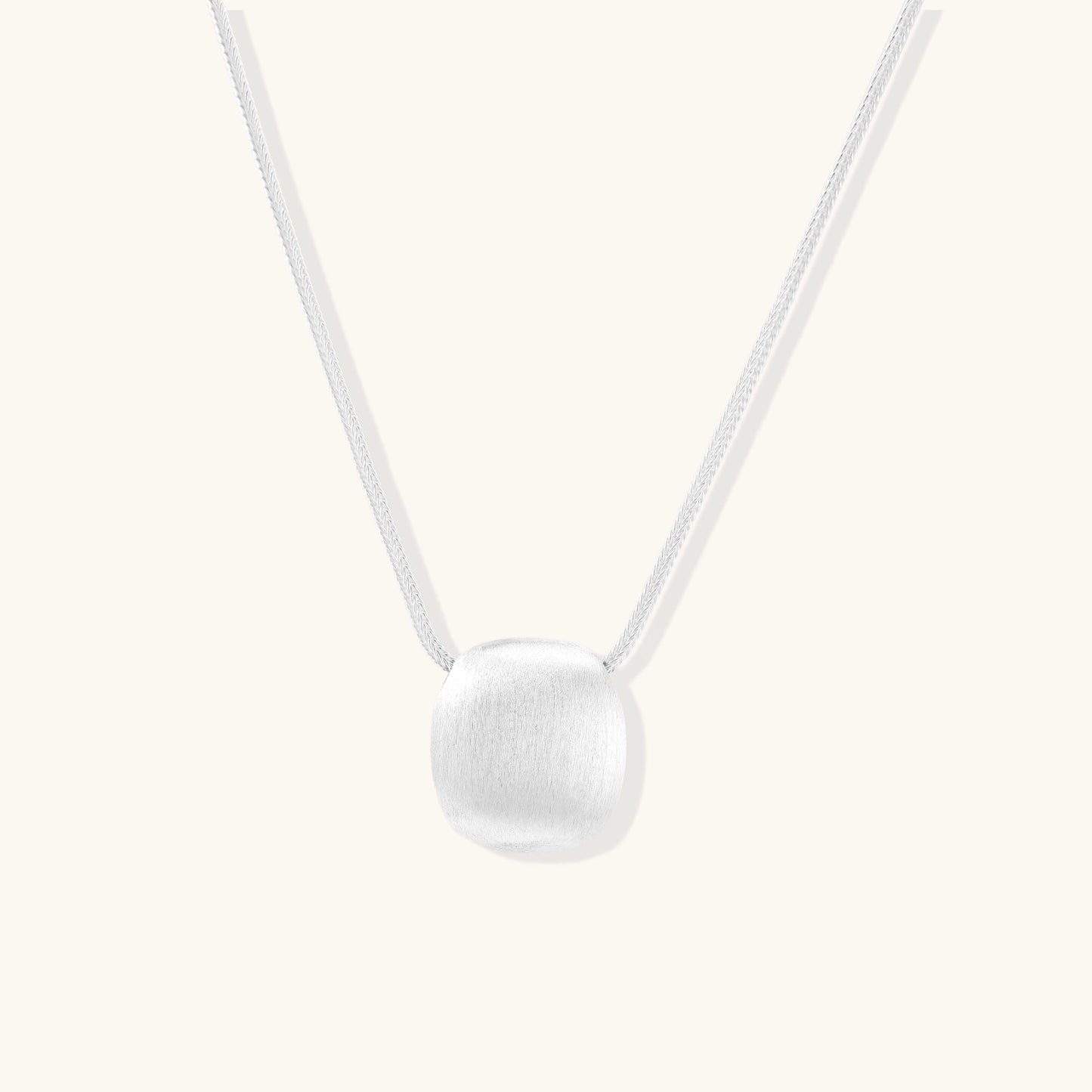 Minimalist sterling silver necklace with brushed square pendant on adjustable chain against white background.