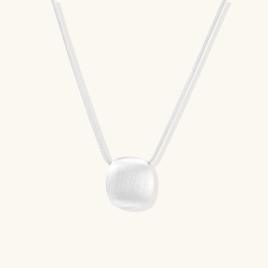 Minimalist sterling silver necklace with brushed square pendant on adjustable chain against white background.