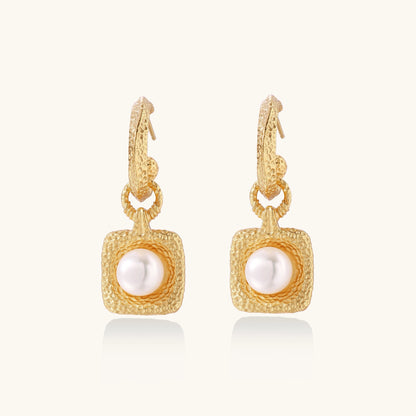 Gold-plated textured hoop earrings with square pendants containing freshwater pearls on white background