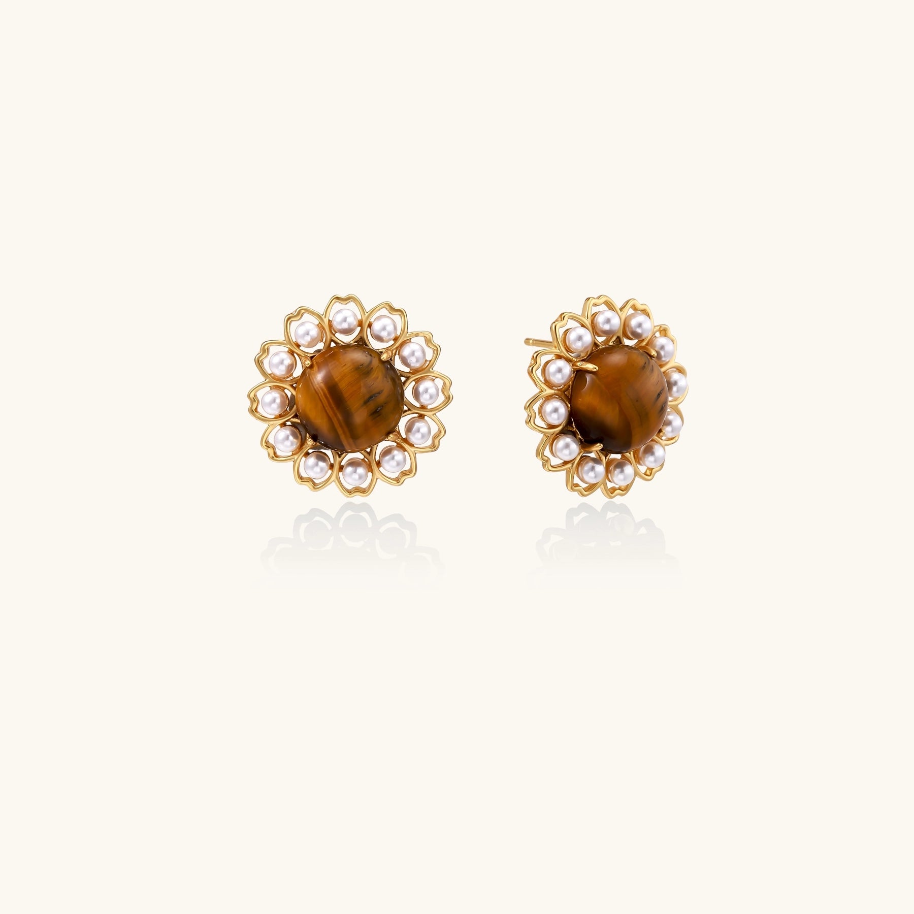 Gold-plated stud earrings with round tiger's eye stones surrounded by small pearls in a floral pattern.