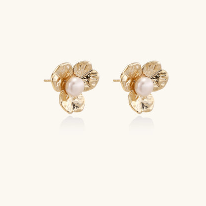 Gold-plated flower stud earrings with freshwater pearl centers on beige background, showing textured petal details.