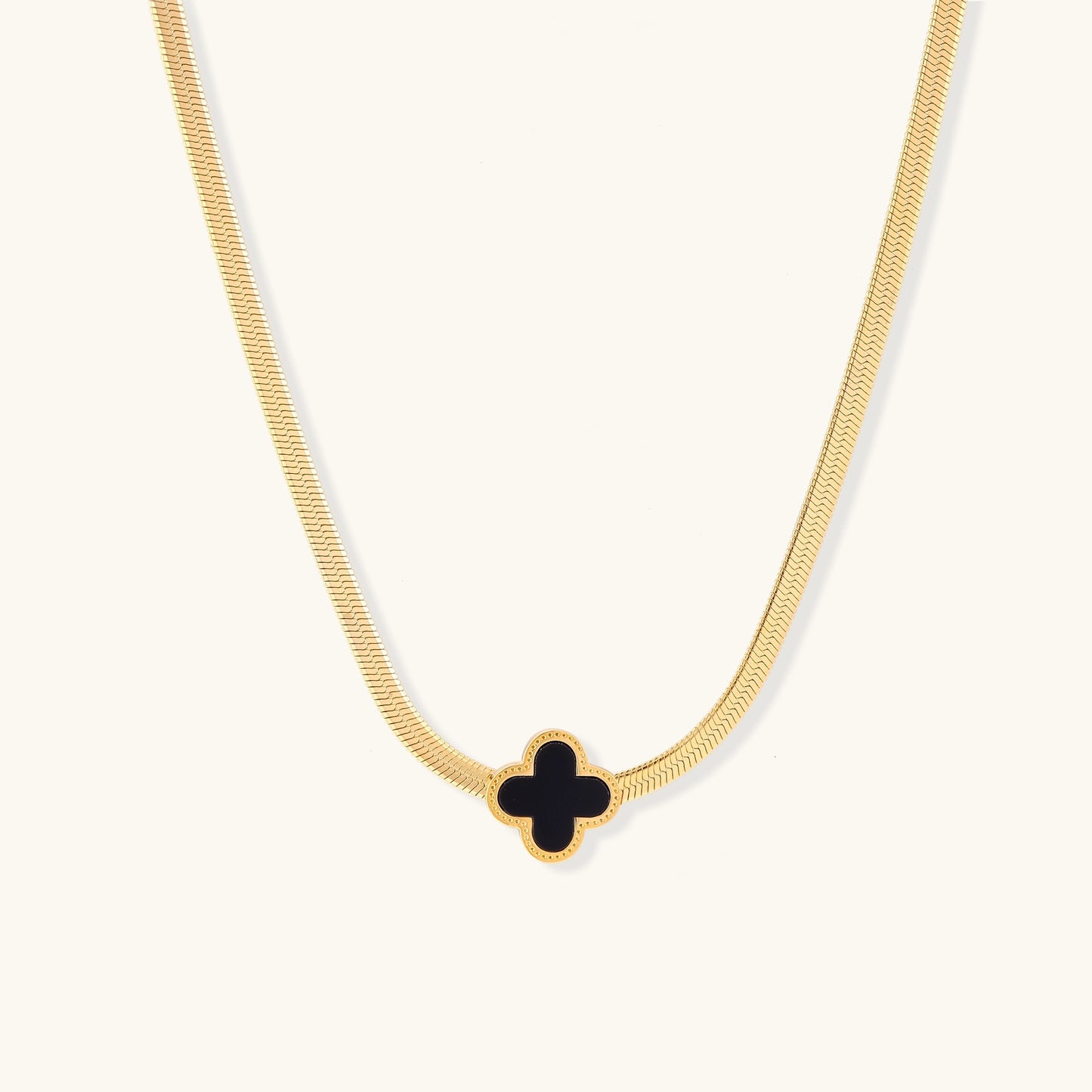Delicate gold-plated chain necklace featuring a black quatrefoil clover pendant on white background.