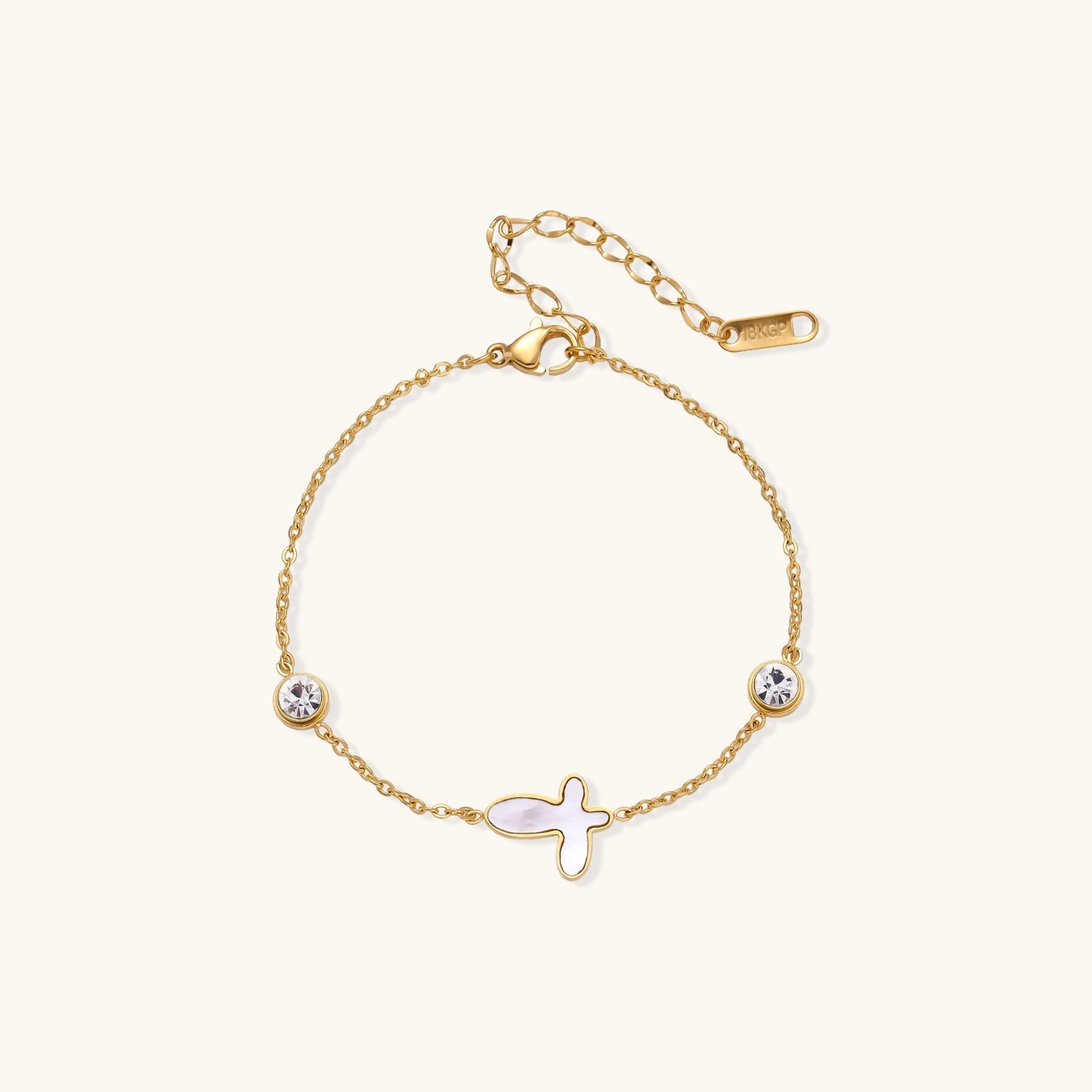 Delicate gold-plated bracelet featuring white mother-of-pearl cross charm and crystal accents on white background.